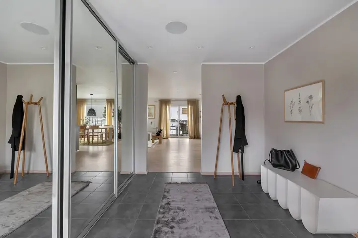 Velkommen inn! Du møtes først av dette romslige flislagte inngangspartiet som leder deg til gjestebad, hall og vider inn til stue og kjøkken